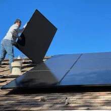 Worker on a roof handling a solar panel