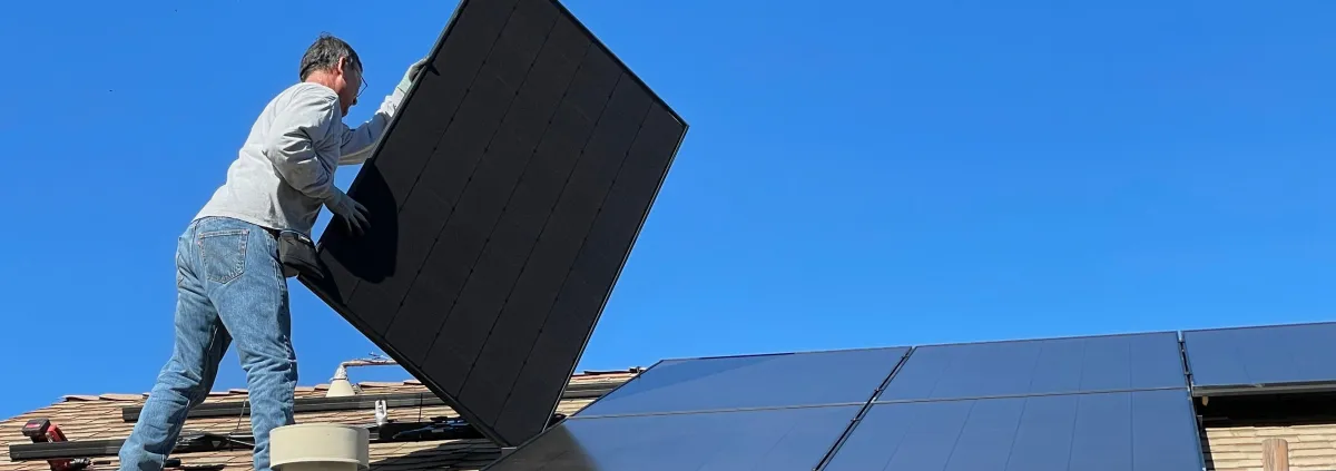 Worker on a roof handling a solar panel